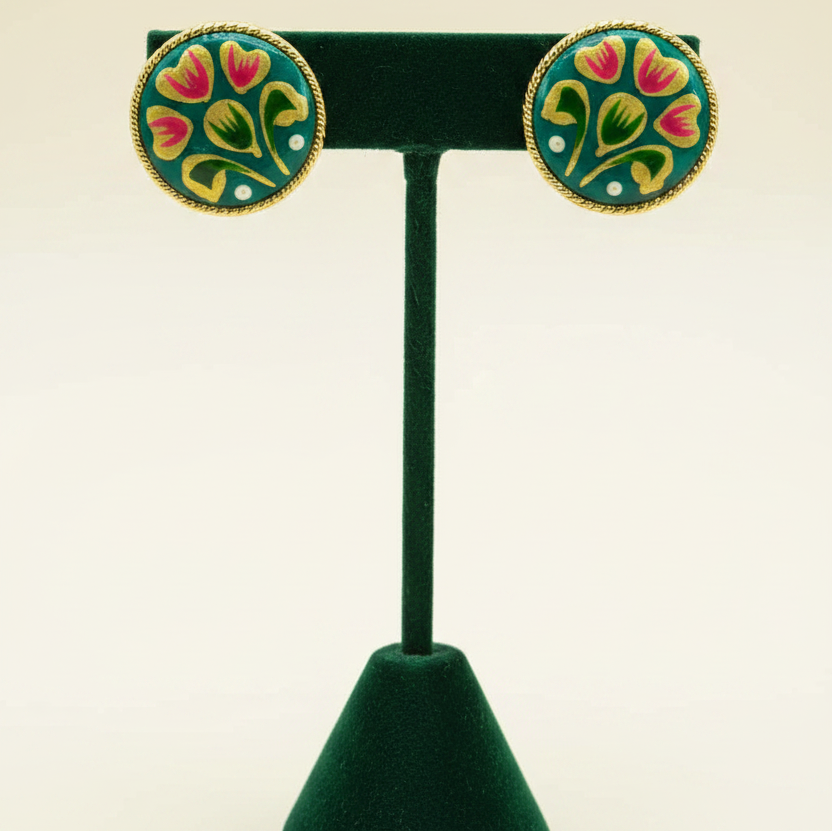 Teal stud earrings on forest green velvet stand